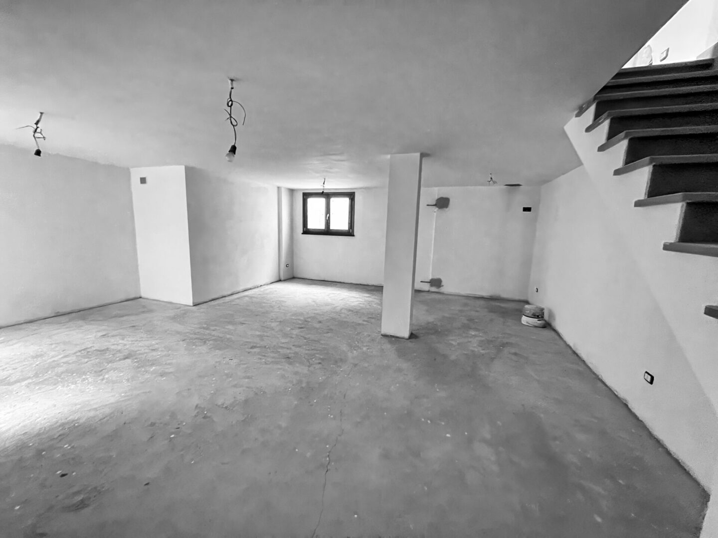 Unfinished basement with bare walls and stairs.