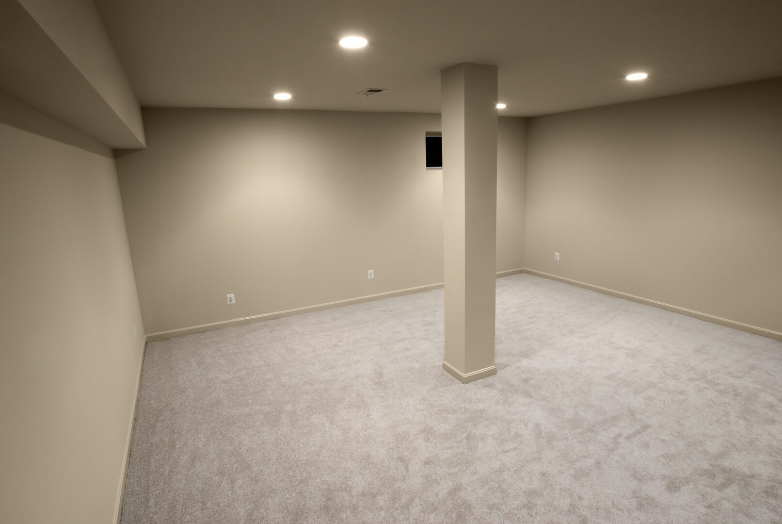 Empty carpeted basement with column and lights.